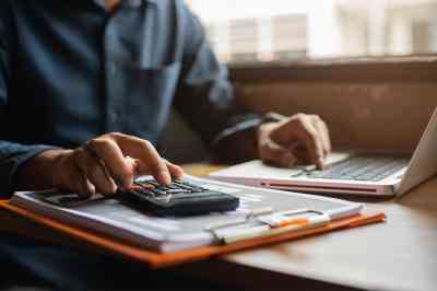 Person mit Taschenrechner und Laptop - © NINENII - stock.adobe.com